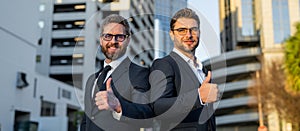 Business men with thumb up outdoor. Young hispanic businessman with arms crossed smiling happy at the city. Portrait of