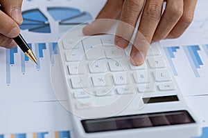 Business men using a calculator to calculate numbers on a company`s financial documents, he is analyzing historical financial dat