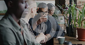 Business men and women sitting at counter in modern cafe talking and drinking coffee in lunch break