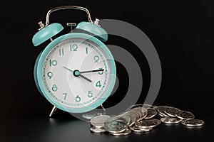 Business metaphor concept time is money concept. alarm clock and coins on black background
