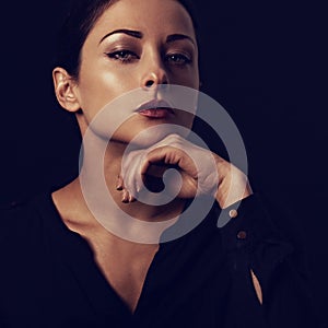 Business mind  thinking woman looking serious with hand under the face in black t-shirt on dark shadow black background. Closeup