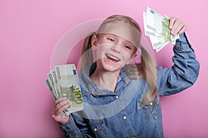 Business and money concept - happy little girl with euro cash money over pink background