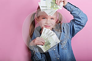 Business and money concept - happy little girl with euro cash money over pink background