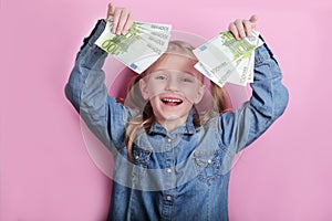 Business and money concept - happy little girl with euro cash money over pink background