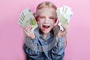 Business and money concept - happy little girl with euro cash money over pink background