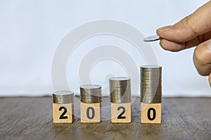 Business, Money, Finance and New year 2020 Concept. Close up of man hand holding a coin and put to top of stack of silver coins on