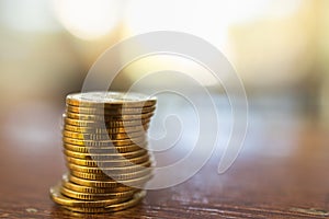 Business, Money, Finance, Security and Saving Concept. Close up of stack of gold coins on wooden table under sunlight with copy