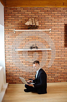 Business man using laptop at home while sitting on floor