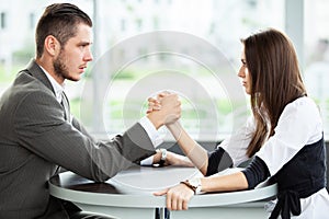 Business and office concept - businesswoman and businessman arm wrestling during meeting in office.