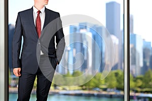 Business and office concept - elegant young fashion buisness man in a blue/navy suit. Downtown background behind