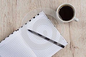 Business and office concept - open blank notebook, pen and cup of black coffee on wooden table. top view