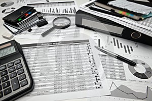 Business office desk closeup - financial reports, analysis and accounting, set of documents, tables and graphs, various items for