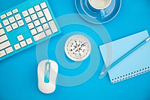 Business office table with business objects of keyboard,mouse,pencil,paper note,compass and coffee cup on blue background