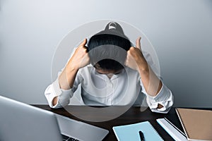 A business office worker is an asian woman is sitting in front of the laptop computer. A businesswoman stressing her body part