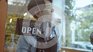 Business owner asian man turning Welcome we are open sign on fronton glass door store