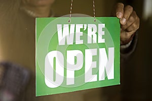 Business owner hanging an open sign at a glass door