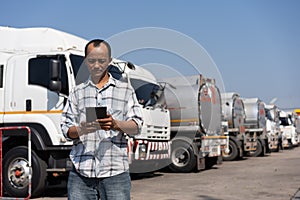 Business owner hold tablet in front of oil truck after performing a pre-trip inspection on a truck. Concept of preventive