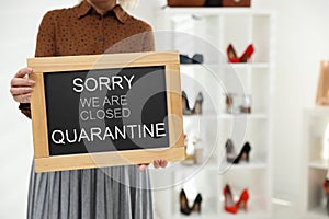 Business owner holding sign with text SORRY WE ARE CLOSED QUARANTINE in boutique