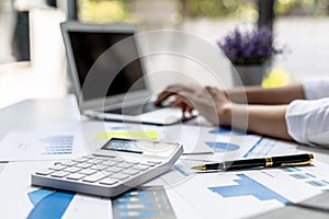 Business owner`s desk, white calculator and company financial charts are placed on the table, businessman checking documents to