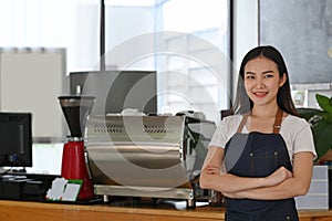 Business owner standing with arms crossed at counter and smiling to camera.