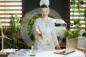 business owner woman in green office giving hand for handshake