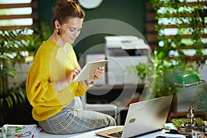 Business owner woman in sweater in green office using tablet PC