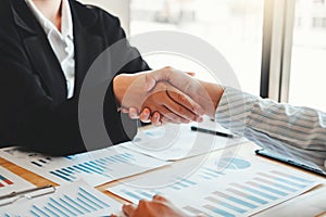 Business partner colleagues shaking hands meeting with new startup project plan Finance and Economy Graph with laptop successful