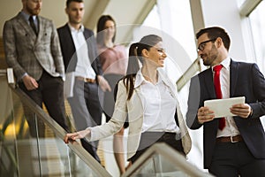 Business partners analyze the business results while walking down the stairs in modern office