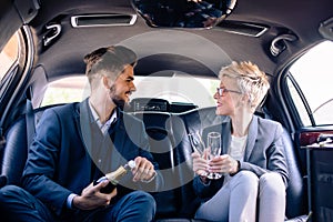 Business partners celebrating in limo with wine