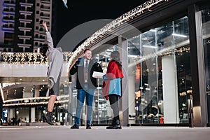 Business partners colleagues cheerfully celebrate a success with papers flying in the air, outside a brightly lit modern