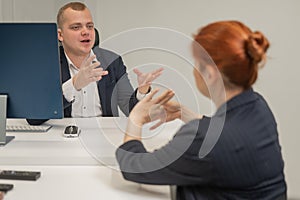 Business partners communicate in sign language. A deaf boss gives a task to a subordinate woman.