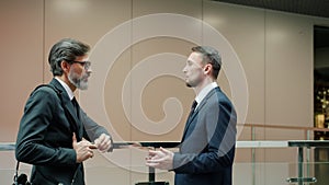 Business partners elegant men in formalwear discussing work in office lobby