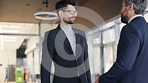 Business partners in formalwear meeting in cafe shaking hands and talking