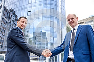 Business partners handshaking near office building outdoors