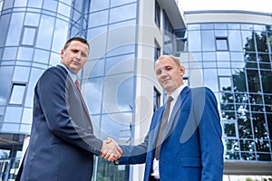 Business partners handshaking near office building outdoors