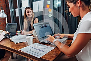 Business partners having a meeting sitting at desk with laptops in conference room