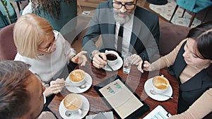 Business partners male and female using tablet pointing at screen and talking at table in cafe