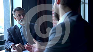 Business partners meeting in office building lobby and greeting with handshake