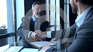 Business partners meeting in office building lobby and greeting with handshake