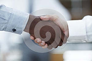 Business partners - Sealing the deal. Close up of a handshake between an African businessman and a Caucasian businessman