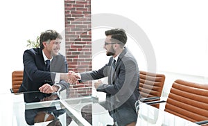 Business partners shake hands after discussing the contract