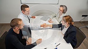 Business partners shake hands. Four business people are negotiating in the conference room.