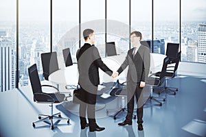 Business partners shake hands in modern conference room