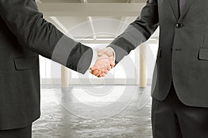 Business partners shake hands in modern empty loft open space of