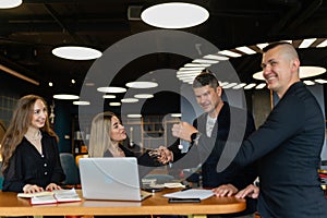 Business partners shake hands during negotiation in office