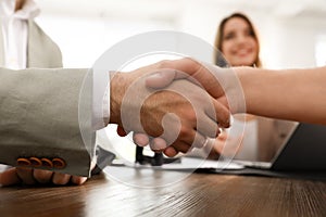 Business partners shaking hands at table after meeting in office