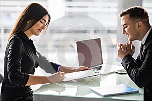 Business partners signing contract at office desk. Woman sign contract in office.