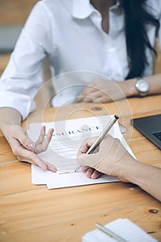 Business partners signing a contract and woman showing where to