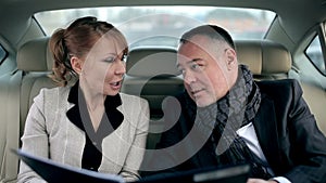 Business partners talking in the backseat of a car