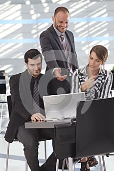 Business partners talking over laptop in lobby